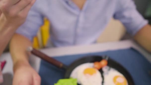 Молодая женщина кормит своего мужа омлетом — стоковое видео